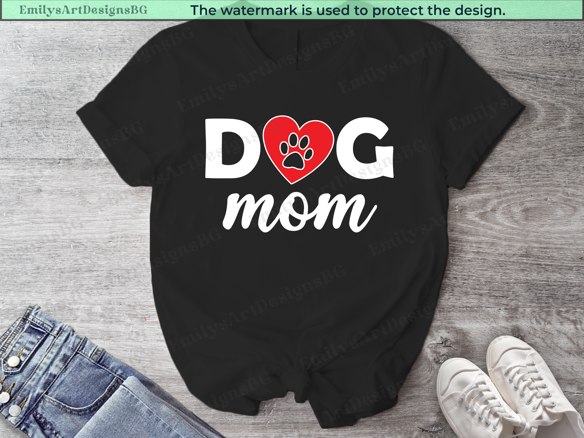 Black t-shirt with 'Dog Mom' text and heart design on a wooden surface with jeans and sneakers.