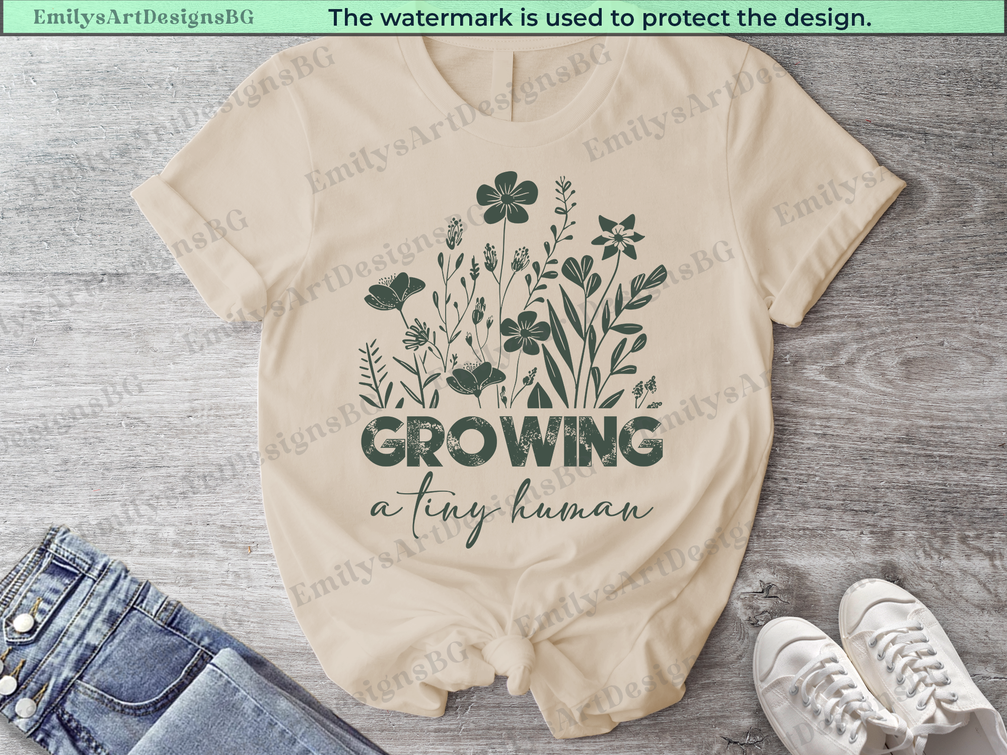 Beige baby romper with floral design and text on a wooden surface, with jeans and shoes in the background.