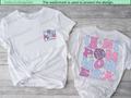 Two white t-shirts with colorful text and graphics on a wooden surface.